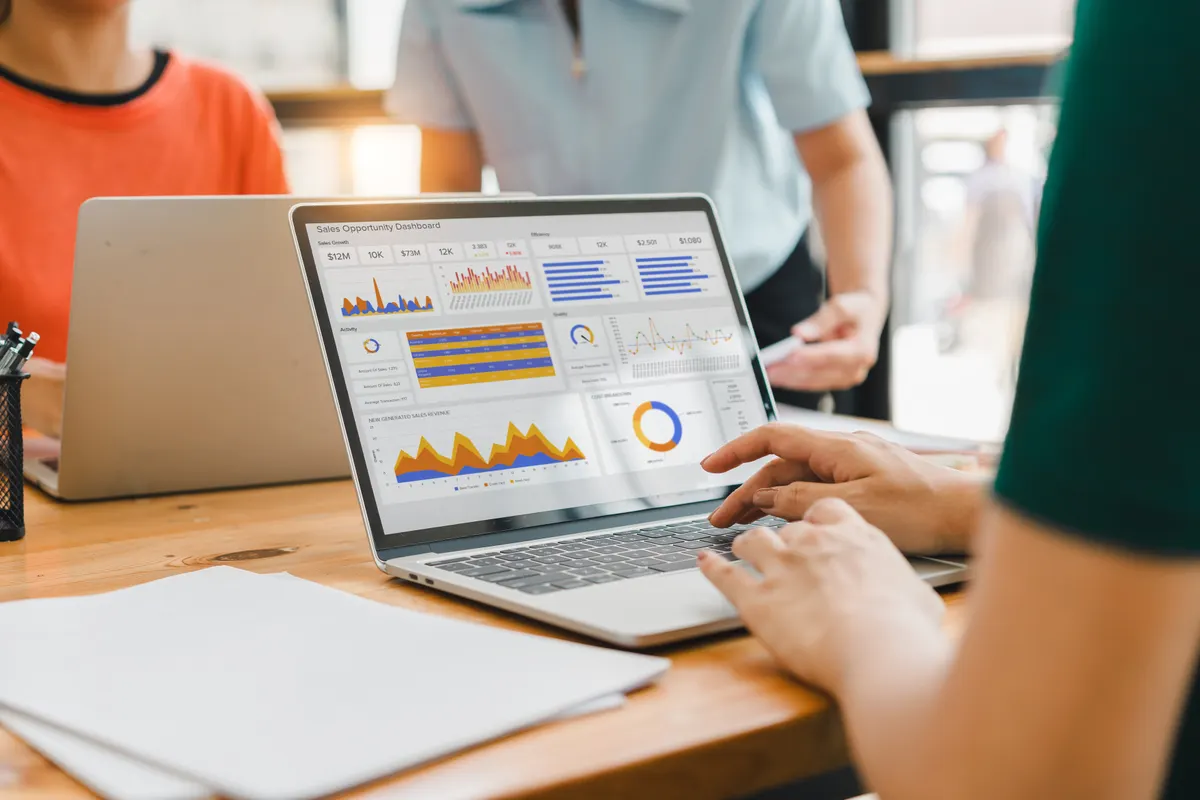 Ecommerce analytics and GA4: person interacts with a digital sales dashboard displaying various performance metrics and analytics.