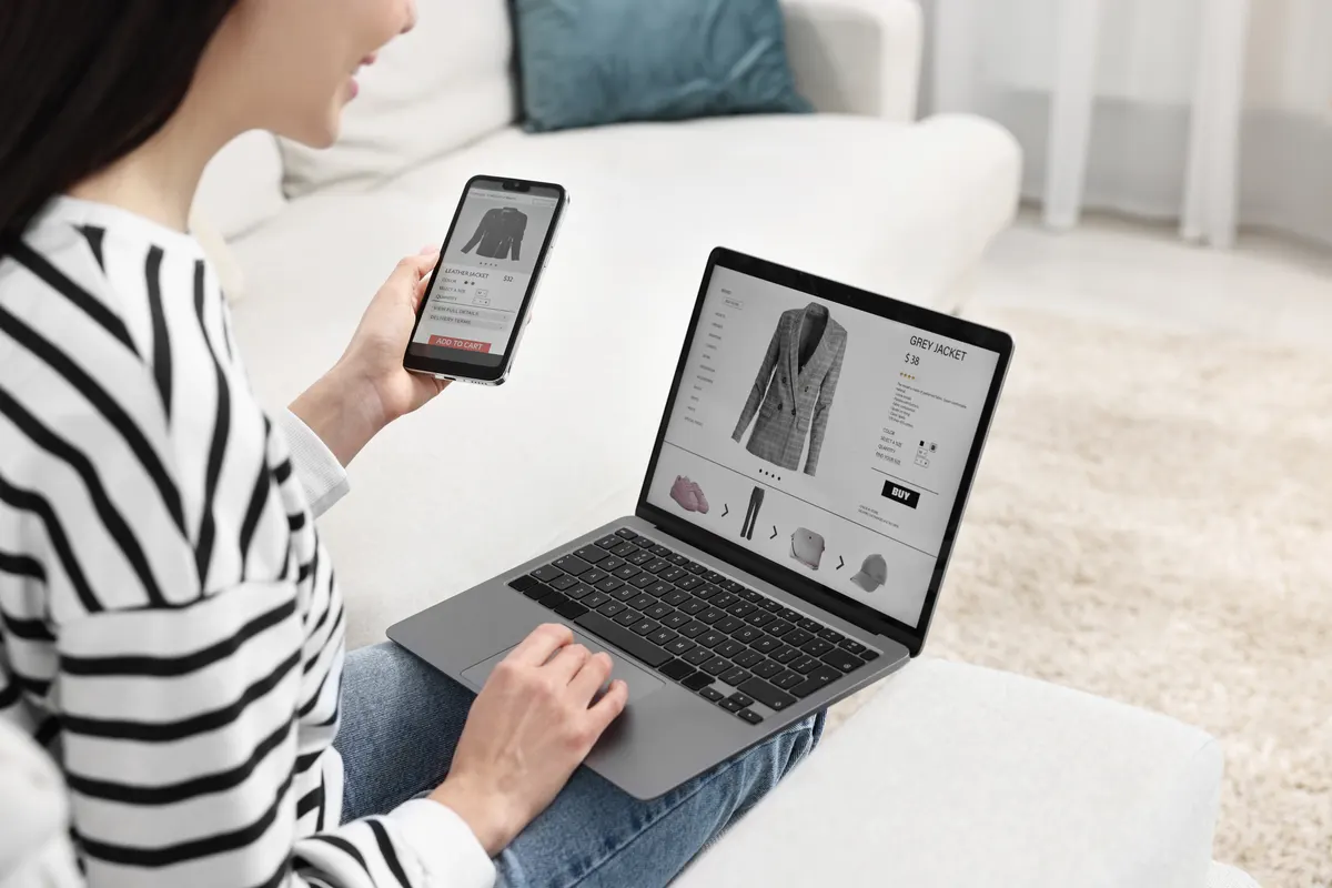 Ecommerce landing pages: woman with smartphone and laptop shopping online indoors, closeup.