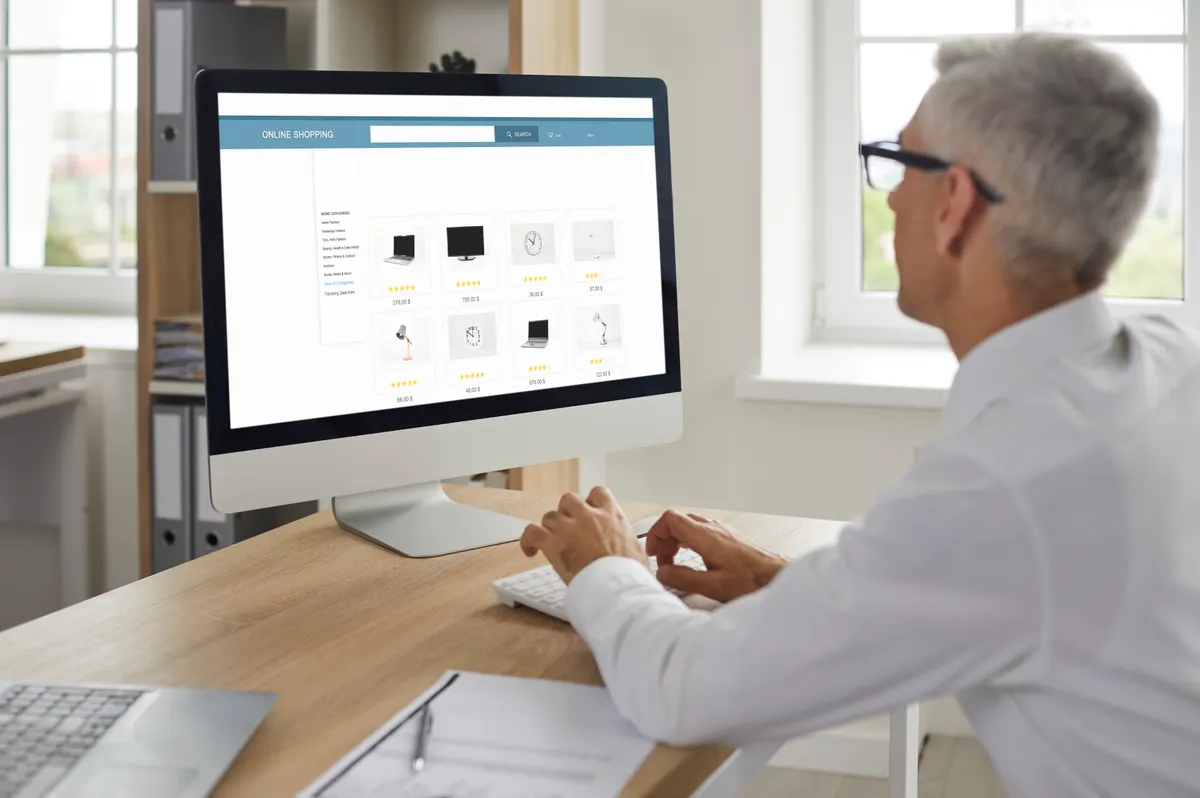 Google shopping ads: man sitting in front of computer and buying new gadgets and office equipment in online store.