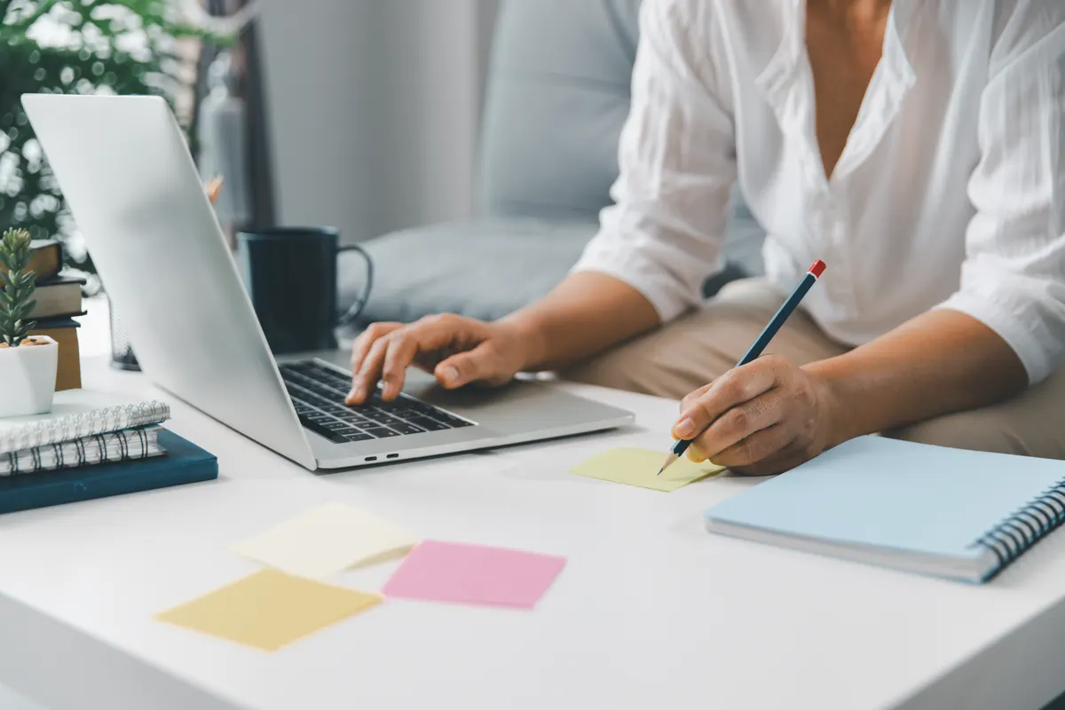 Klaviyo flows: hands using a laptop and sticky notes for brainstorming on a white desk. Ideal for project management, creative thinking, and modern education concepts for students and entrepreneurs.