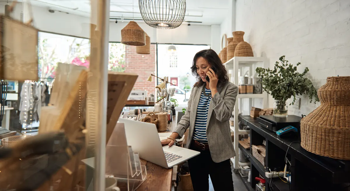Shopify SEO: smiling Asian woman talking on a cellphone in her store.