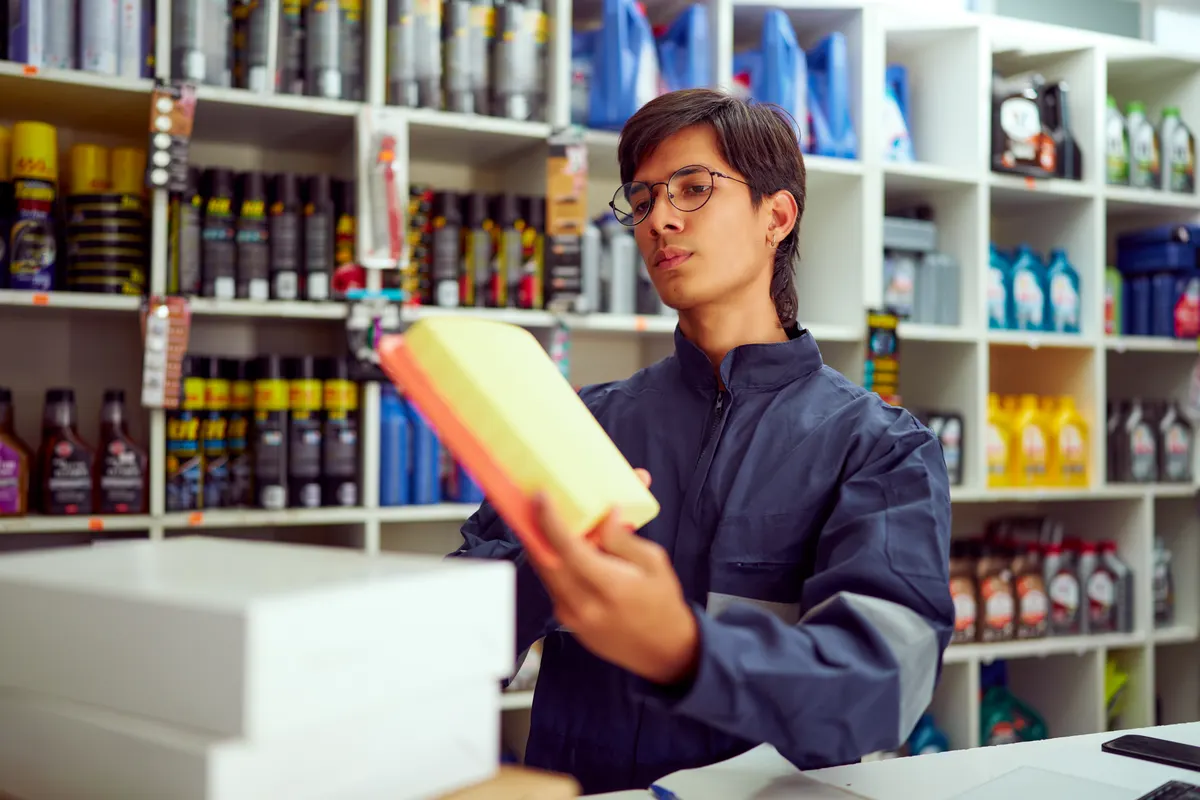 Automotive & marine ecommerce marketing agency: mechanic holding new air filter in auto parts store.
