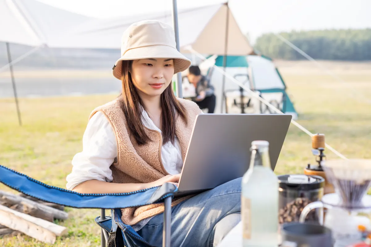 Sports & outdoor ecommerce marketing agency: woman Using Laptop While Camping Outdoors.