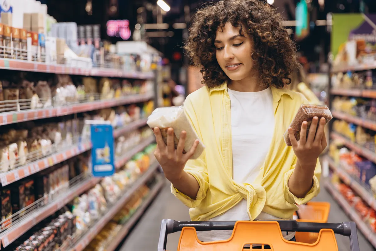 How price competitiveness affects shopping ads: woman choosing between white and brown rice in supermarket.