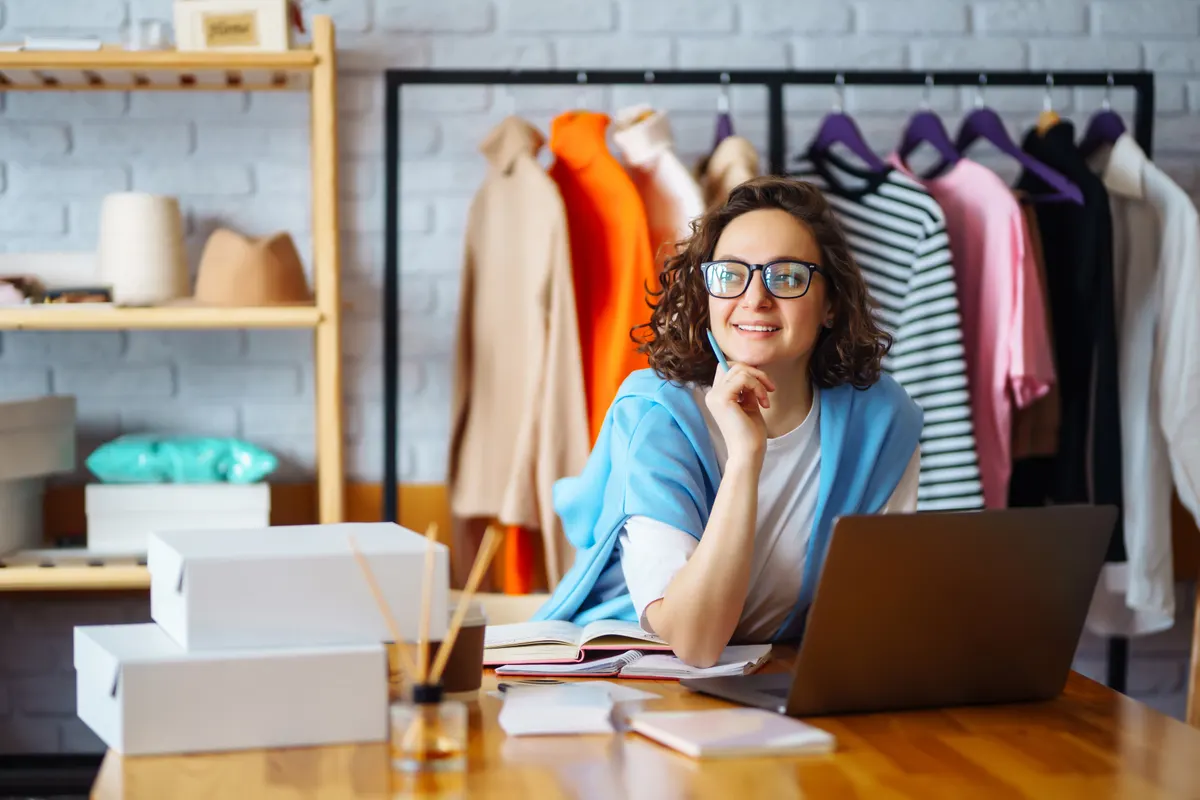 How to brief an agency on your store: smiling woman takes notes of orders from with laptop.