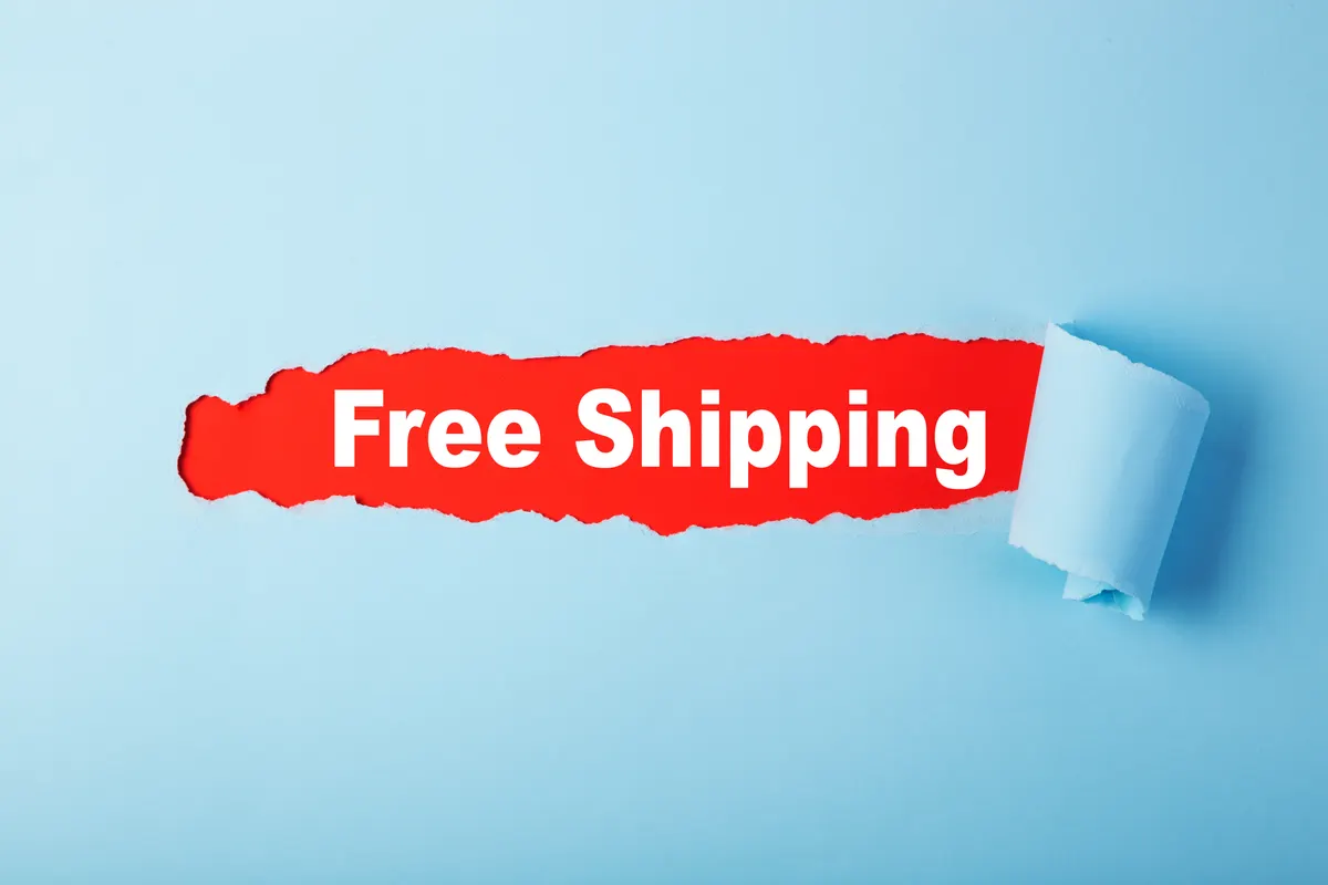 How to test a free shipping threshold: red hole in blue paper with Free Shipping word. Torn paper with space for a message.