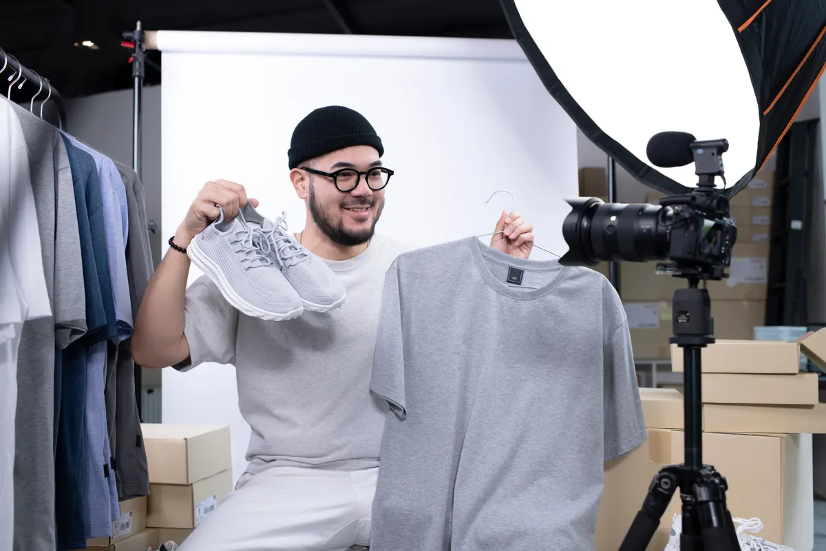 What apparel brands get wrong in product feeds: asian man blogger or vlogger looking at camera reviewing product.