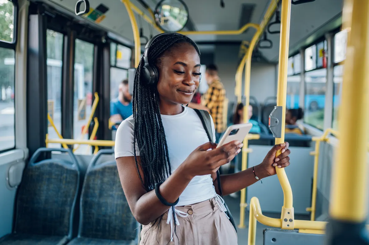 What shoppers ask ChatGPT before they buy: african american woman using smartphone while riding a bus.