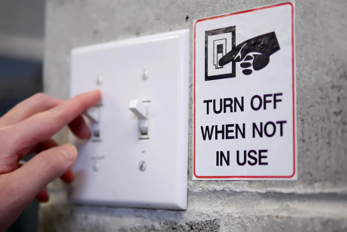 When to turn off a campaign: woman preparing to turn off light switch by saving power concept.