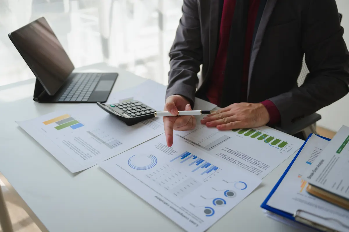 Why ROAS is the wrong north star: professional analyzing financial data, using calculator and tablet near graphical charts at workplace.