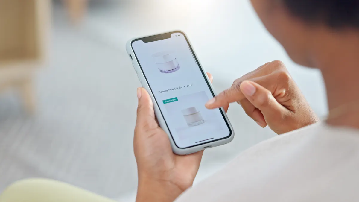 Why speed matters more on product pages than the homepage: person, hands and phone in ecommerce, beauty or products on sale or discount at home. Closeup of shopper looking at cosmetics, lotion or cream in online shopping on mobile smartphone app in house.