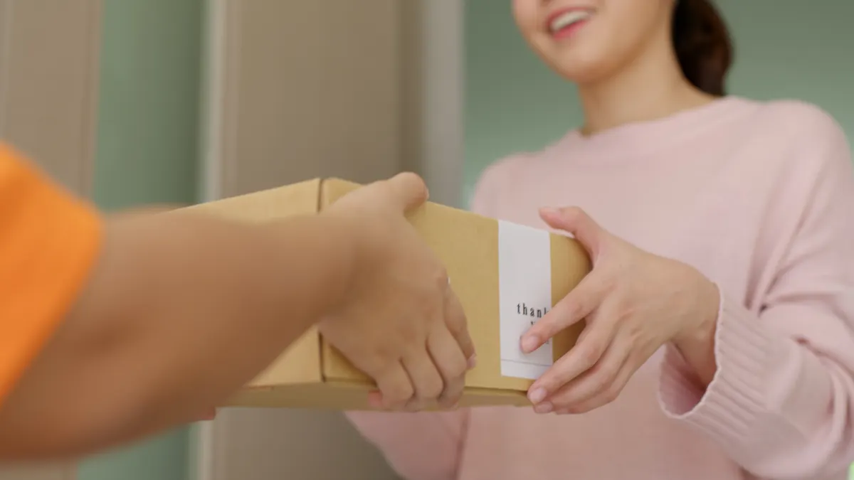 A parcel with a thank-you sticker being handed to a customer