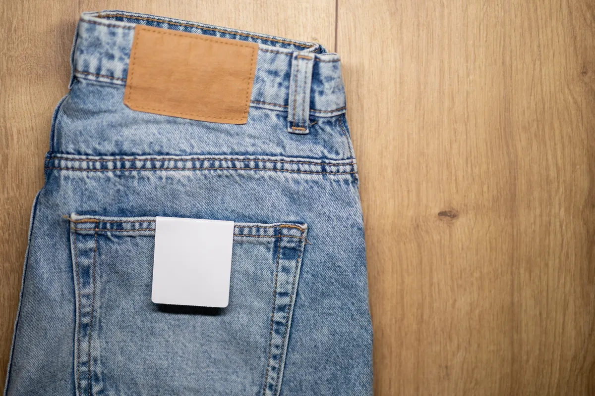 Denim marketing agency: denim jeans with a leather patch and a blank tag on the back pocket, displayed on a wooden surface for product presentation. mockup with copy space.