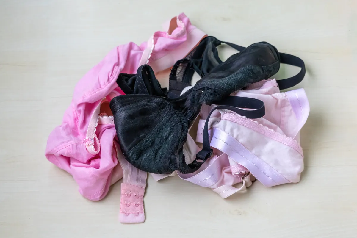 Lingerie & intimates marketing agency: soft, comfortable cotton bras in pink, black, and peach colors displayed on a wooden surface. Ideal for fashion, lingerie, and intimate apparel concepts.