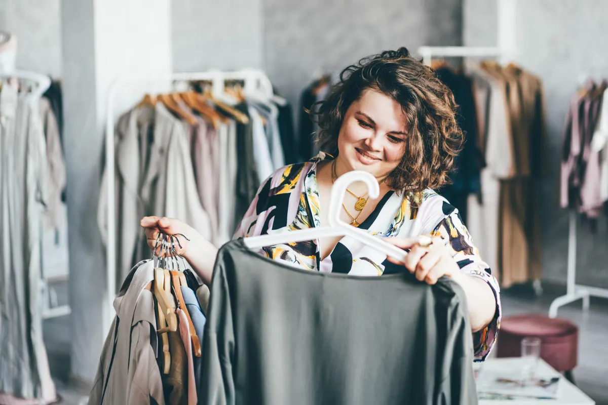 Plus-size clothing marketing agency: plus Size Woman Choose Fashioned Dress in Store. Plus size women shopping.