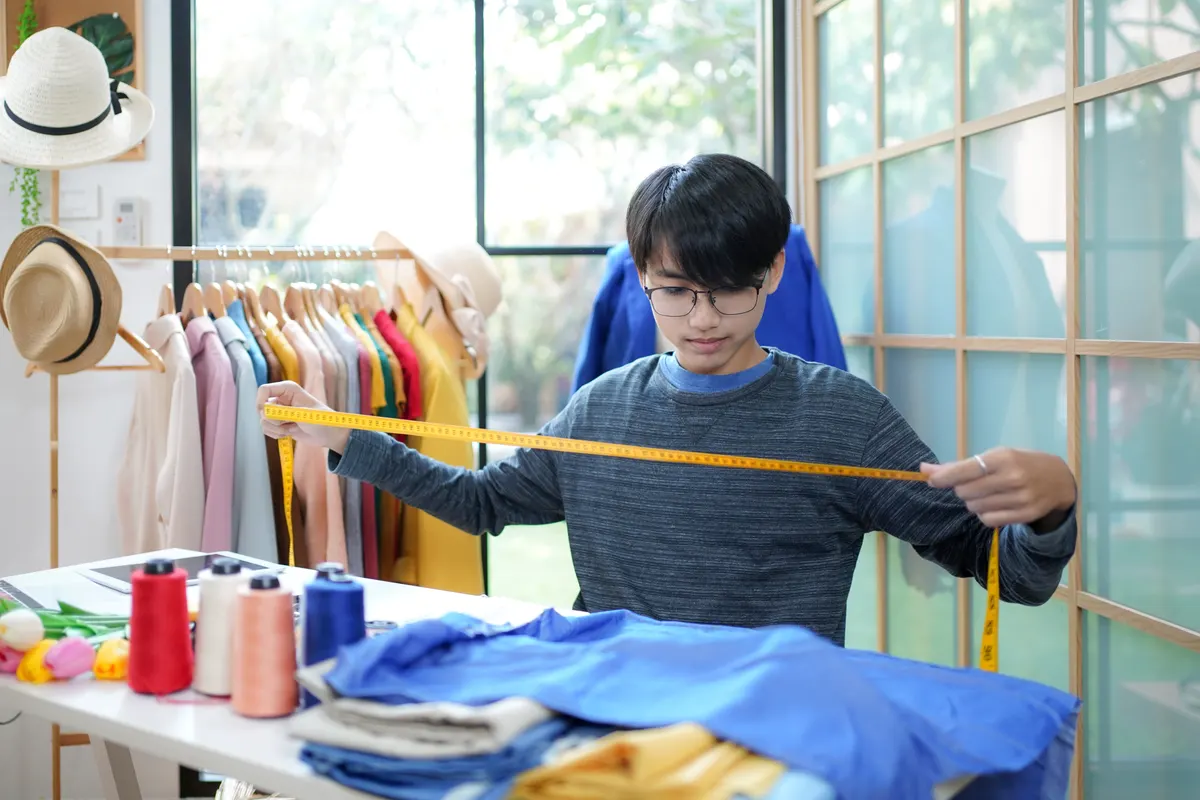 Vintage clothing marketing agency: trainee asian teenage man fashion designer vocation and education work on designer in the showroom,.