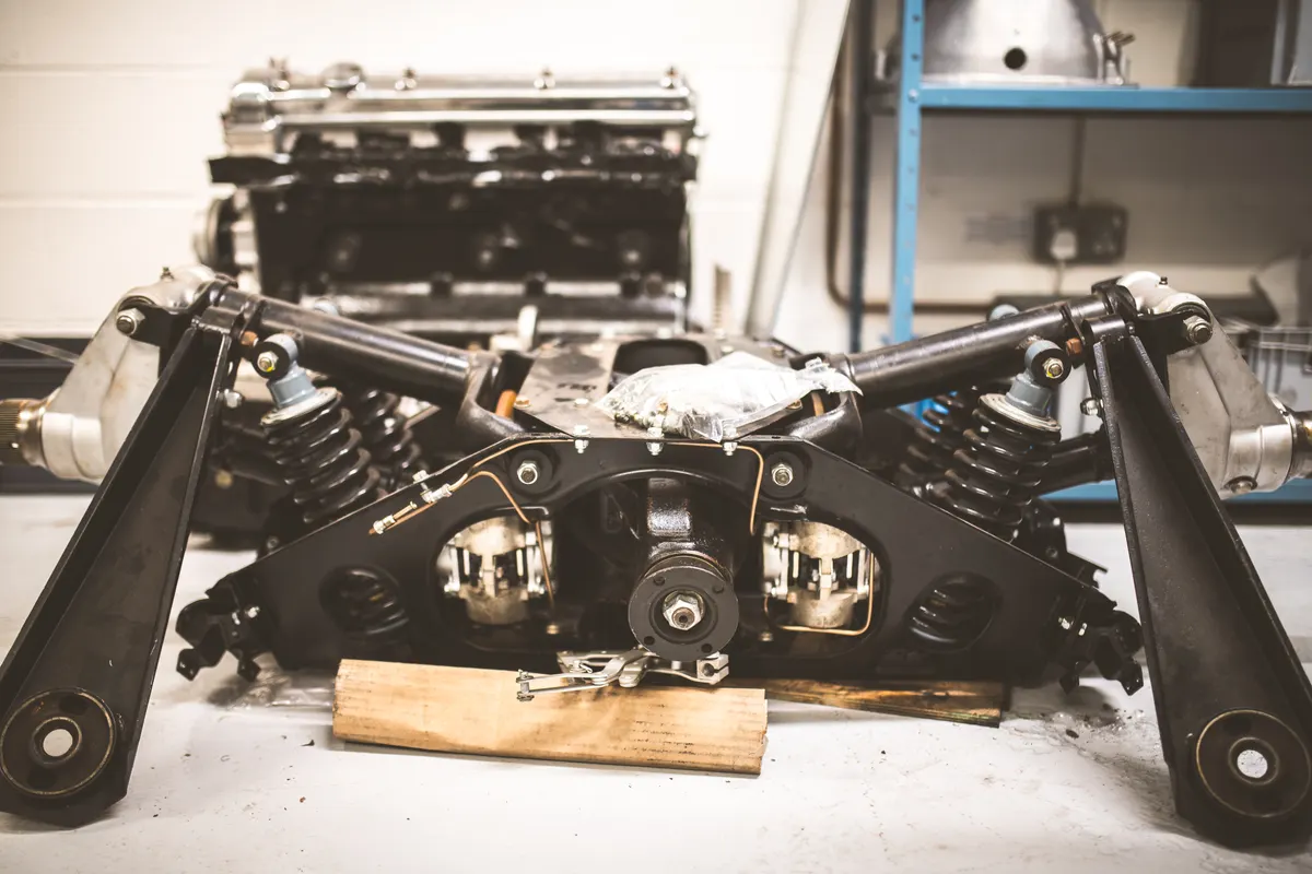 Classic car part marketing agency: vintage automotive suspension system and engine assembly in workshop setting.