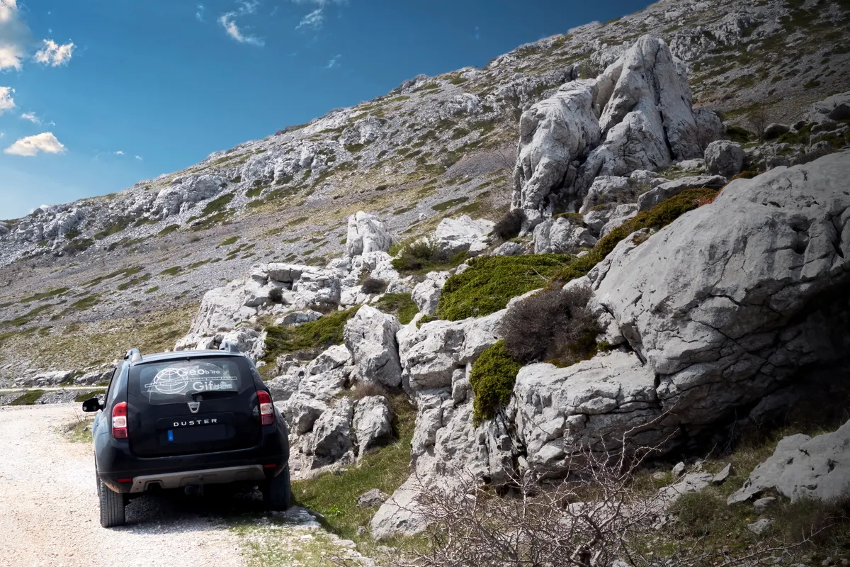 Off-road accessory marketing agency: black off-road vehicle next to slope with large limestone boulders in Velebit mountains.