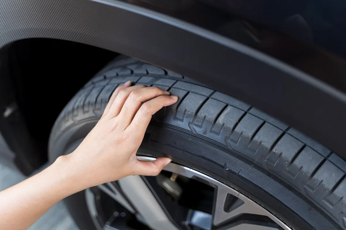 Online tire store marketing agency: hand woman checking air pressure air car tire. Close-up of unrecognizable woman checking the status of his car's tires.