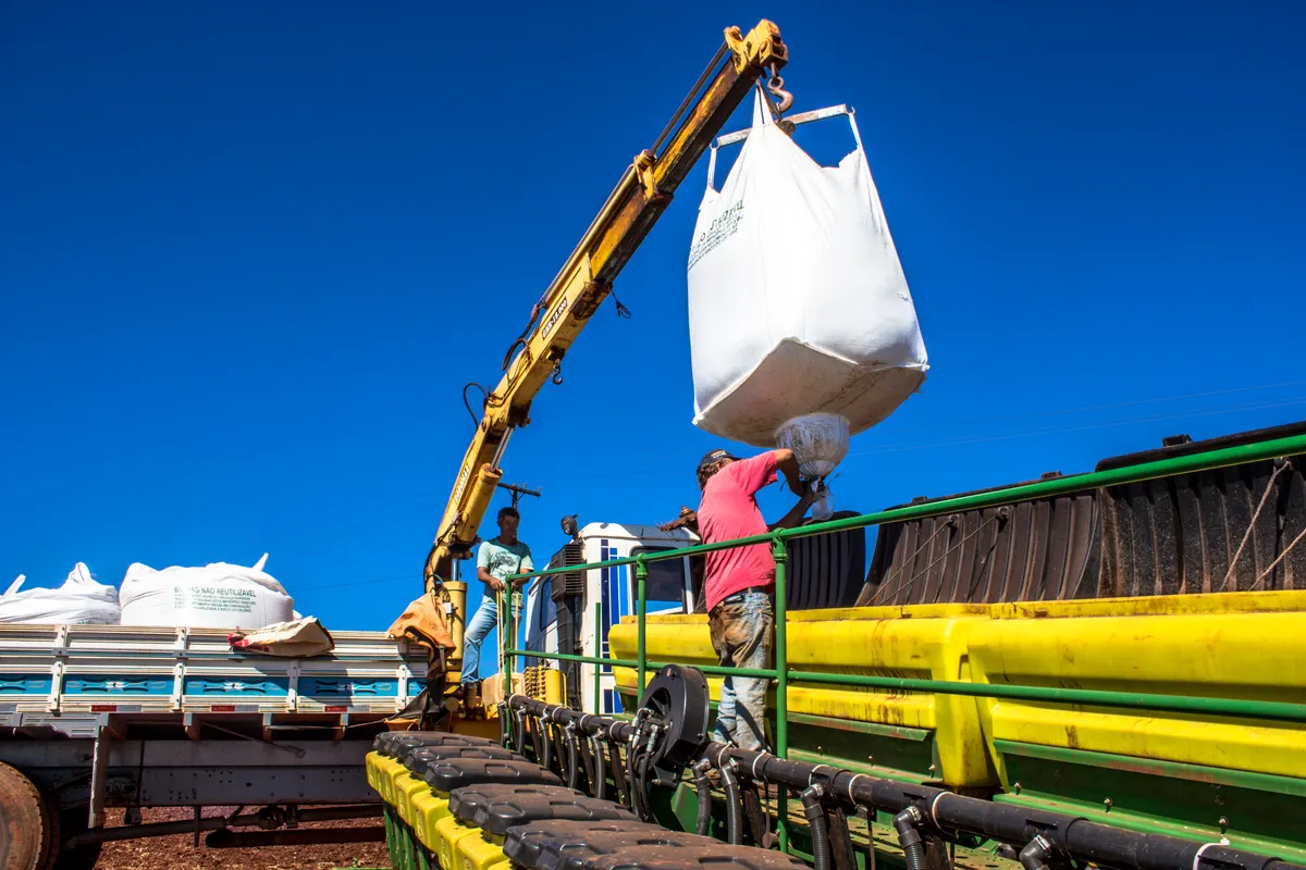 Agricultural supply marketing agency: worker carry an agricultural machine with fertilizer in Parana, Brazil.