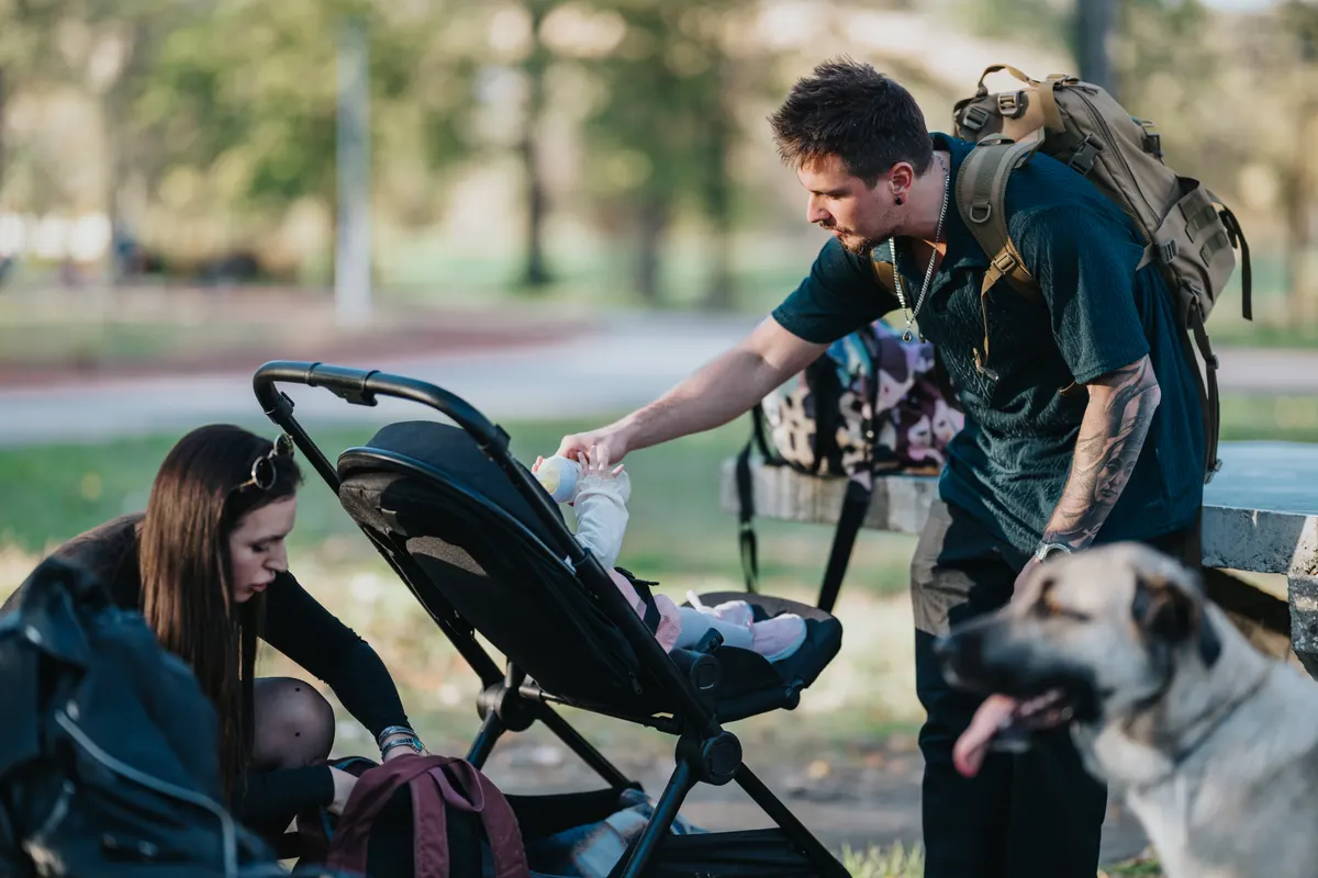 Baby gear marketing agency: loving family in the park in autumn sharing a moment with baby and dog.