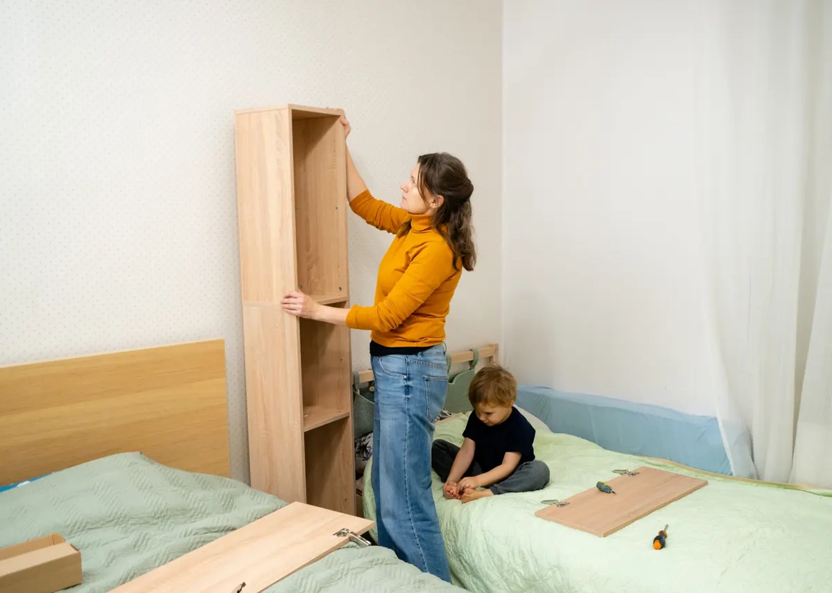Kids' furniture marketing agency: woman assembling furniture in bedroom, child observing.