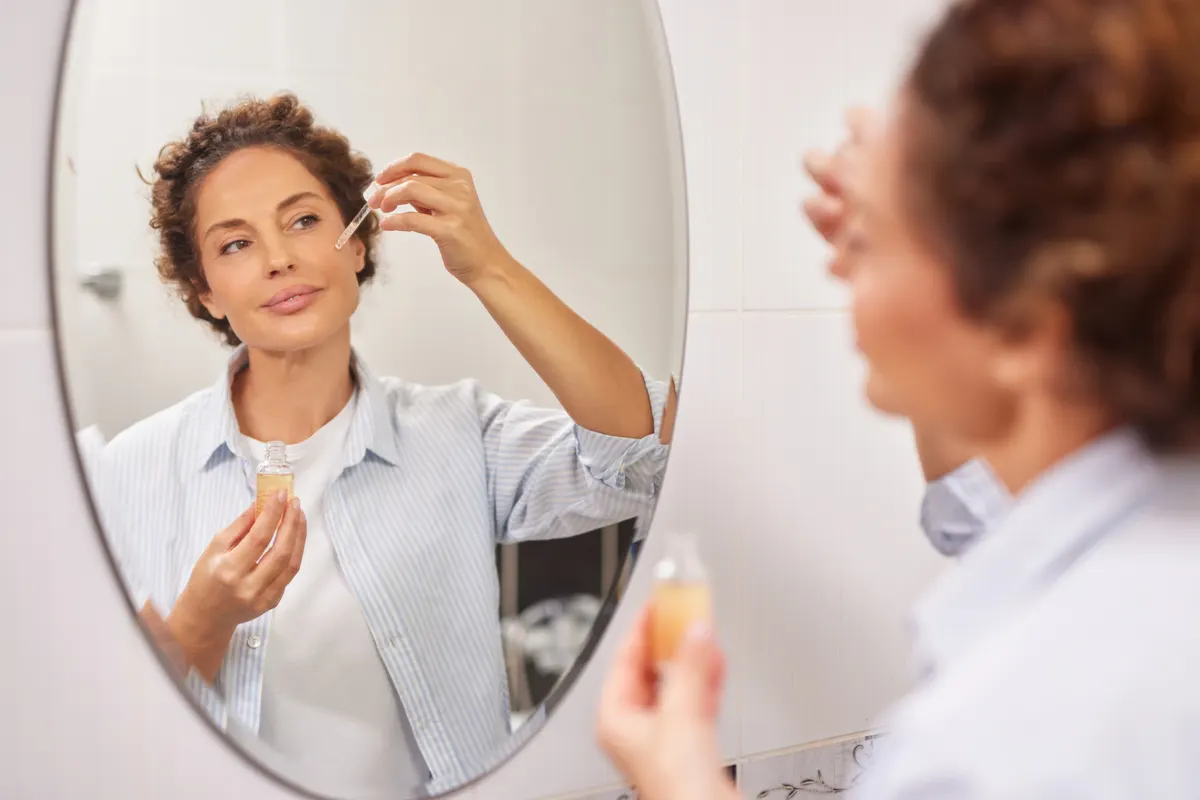 Anti-aging skincare marketing agency: woman doing daily skincare routine applying face serum.