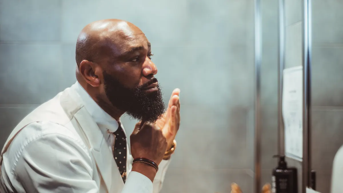 Beard care marketing agency: african guy grooming his fine beard.