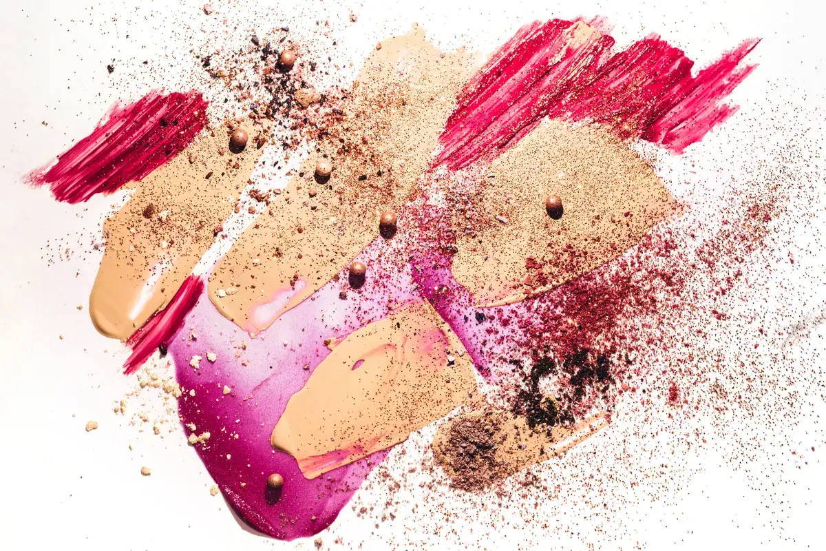 Makeup marketing agency: beauty concept with Smudged makeup foundation, broken shadows, lip gloss and sparkles on white background.