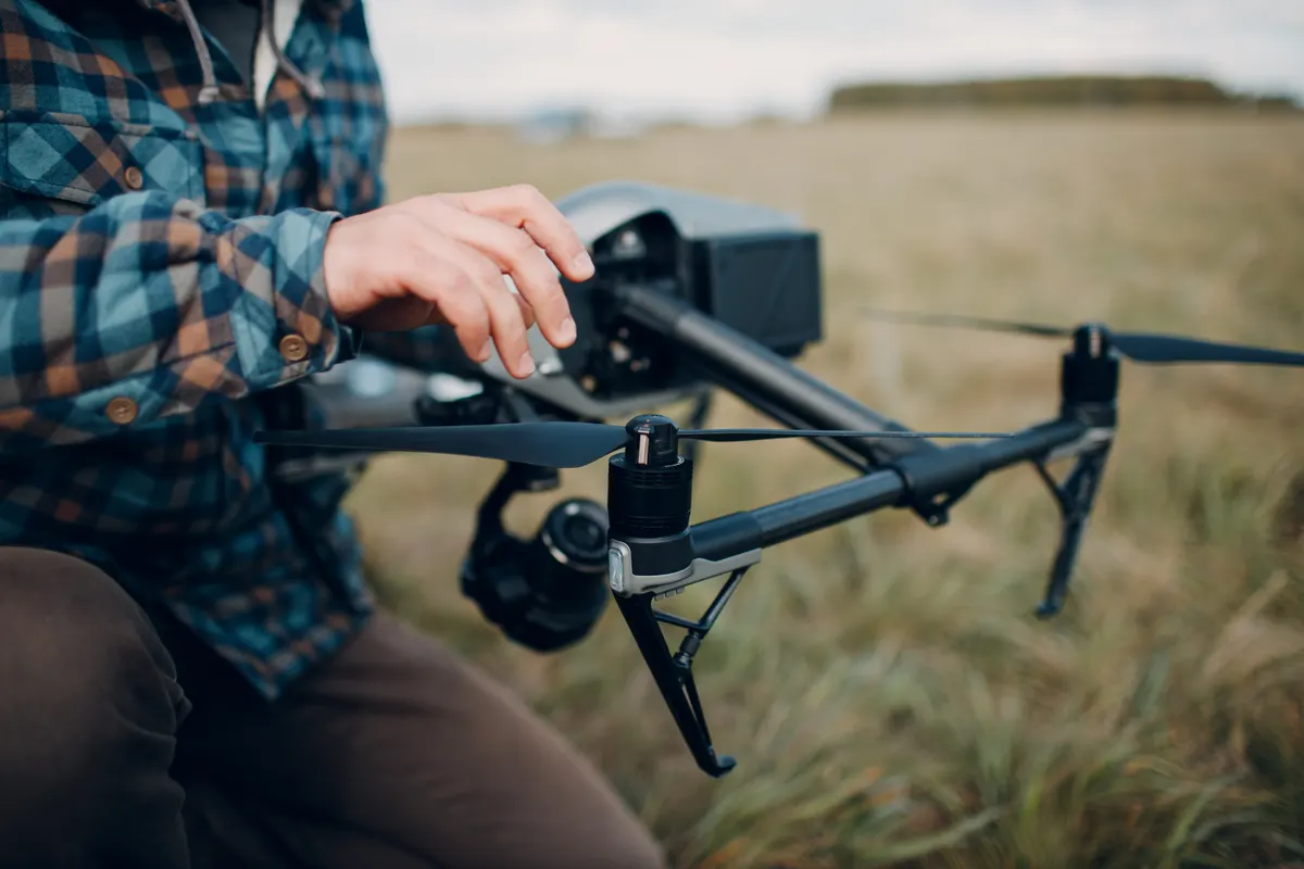 Drone marketing agency: man pilot checking quadcopter drone before aerial flight and filming.