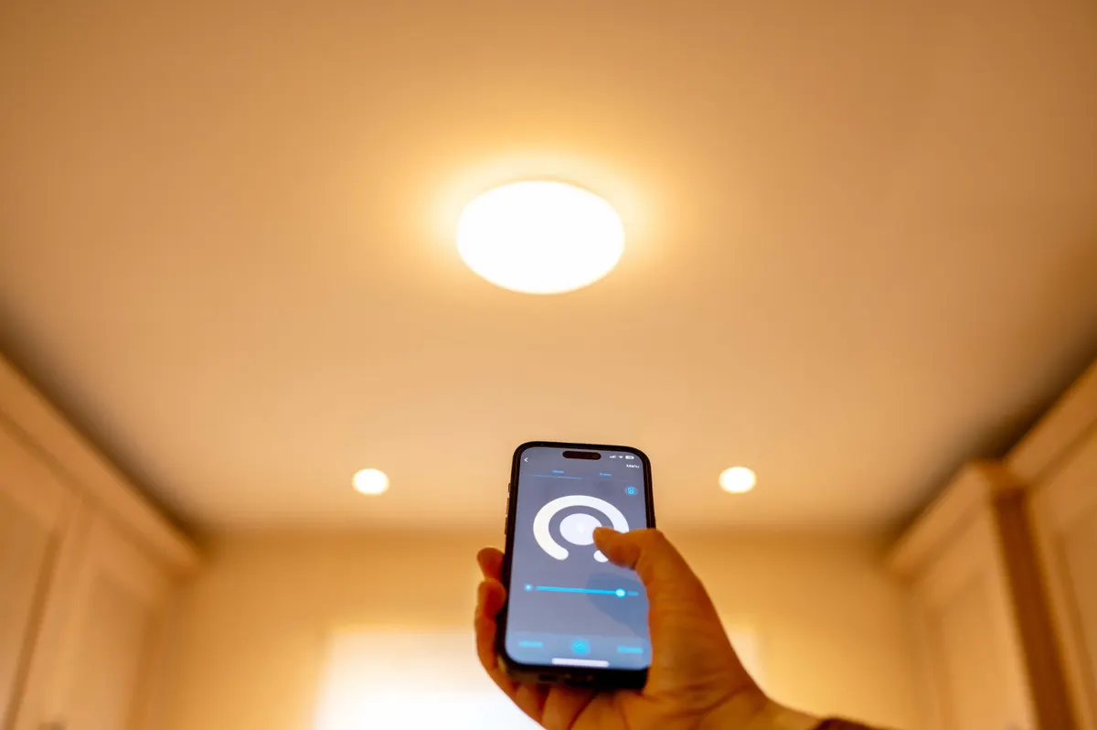 Smart lighting marketing agency: woman controlling smart lighting at home using smartphone. Concept: smart home, control lighting from smartphone.