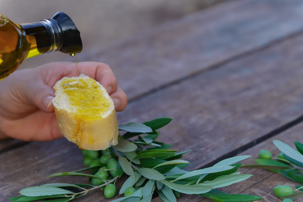Gourmet pantry & olive oil marketing agency: hand pouring olive oil on fresh bread.