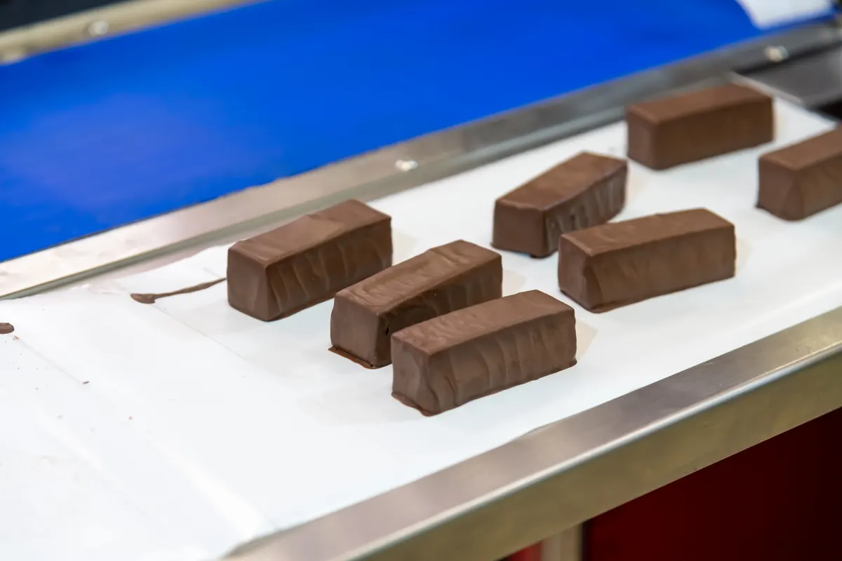 Protein bar marketing agency: chocolate bars moving on conveyor belt during production in factory.