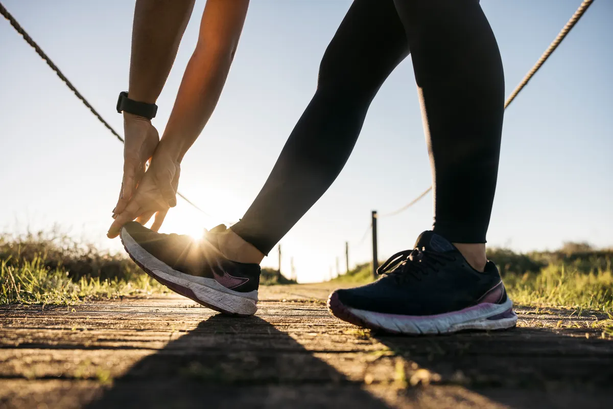 Running shoe marketing agency: woman tying running shoe preparing for outdoor workout.