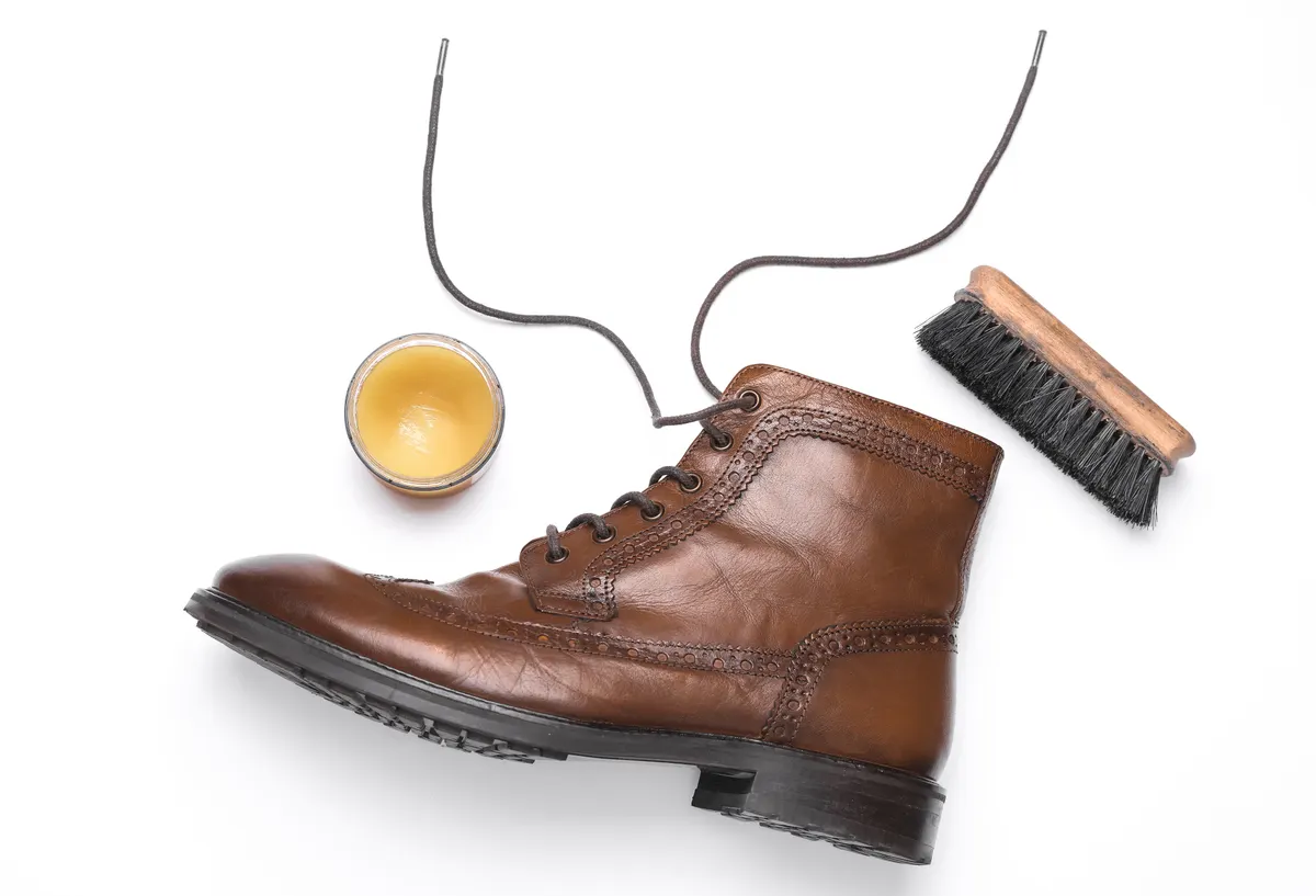 Shoe care product marketing agency: shoe care products and leather boot on white background.