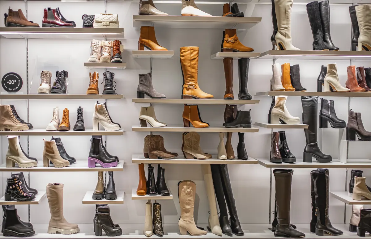 Wide-fit shoe marketing agency: women's boots on the shelves in the store. Store with fashionable women's shoes. Leather autumn-winter boots.