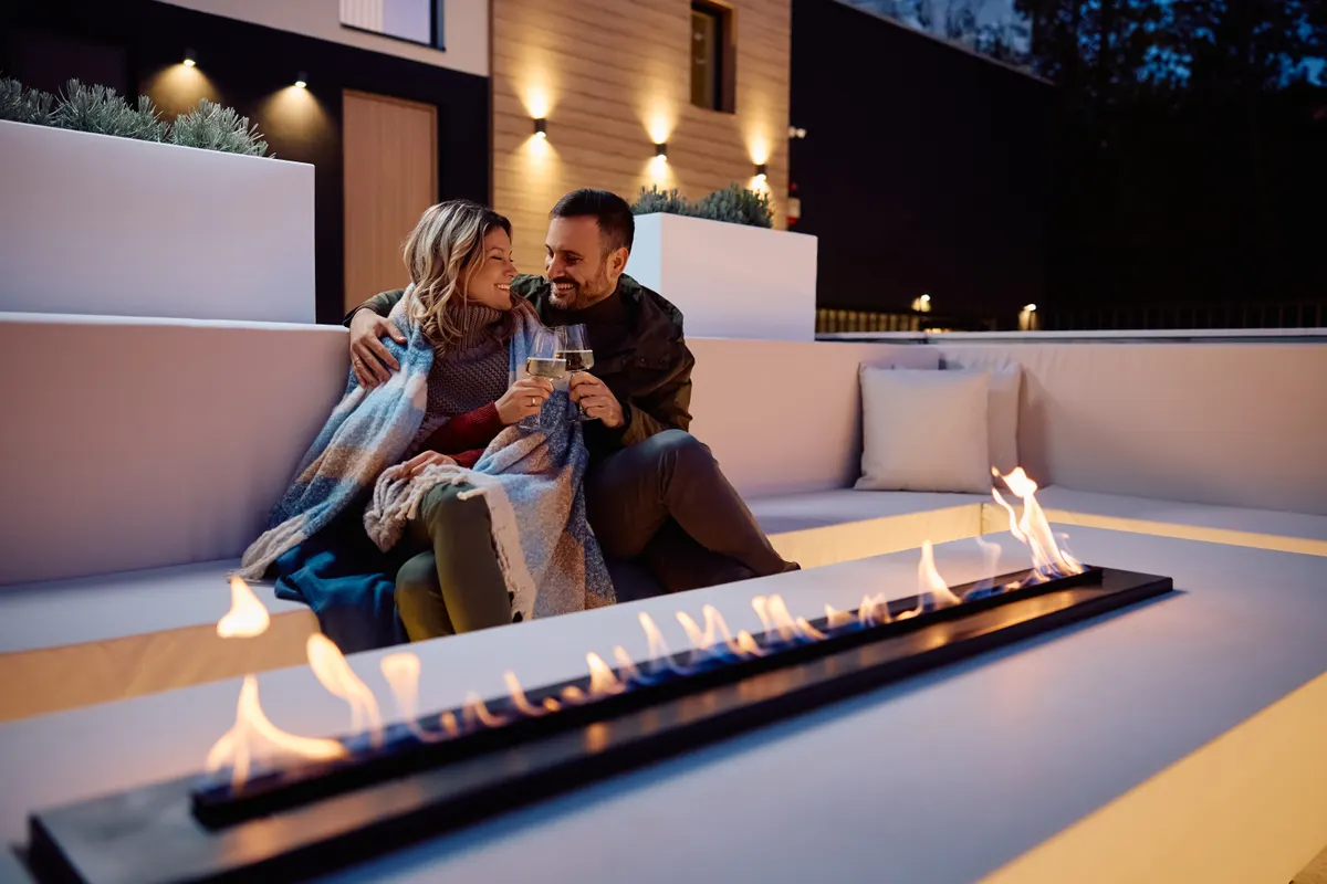 Patio heater & fire pit marketing agency: happy couple toasting while enjoying in romantic evening by fireplace on a patio.