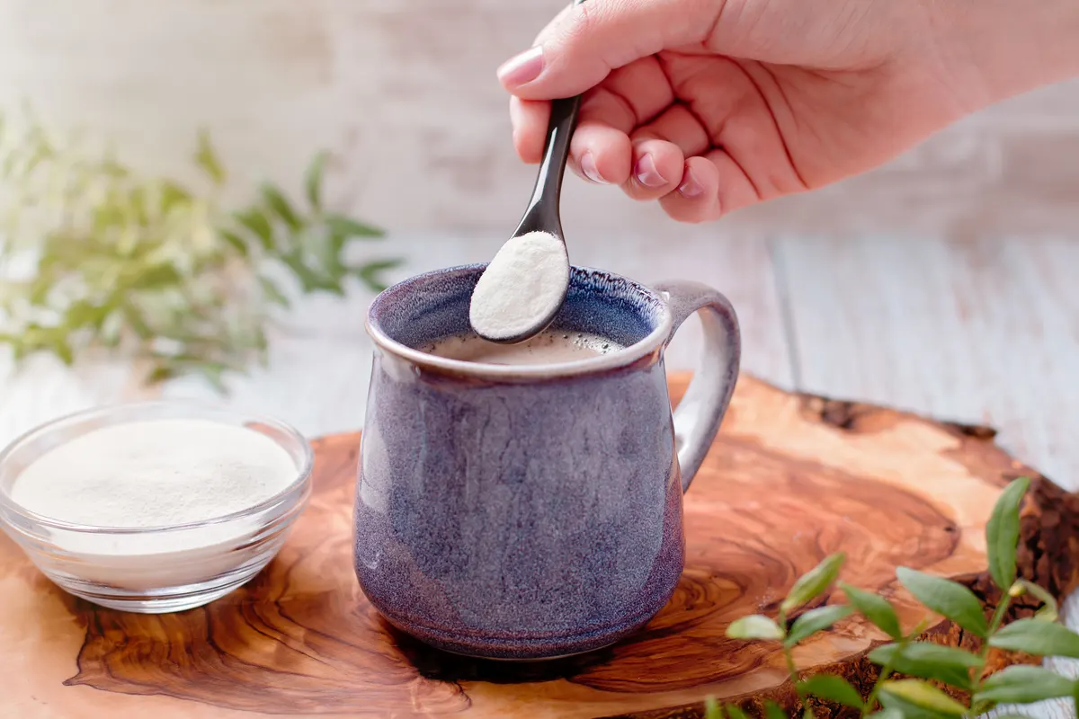 Collagen marketing agency: woman adding collagen powder to her morning coffee. Beauty collagen supplement, additional collagen intake.