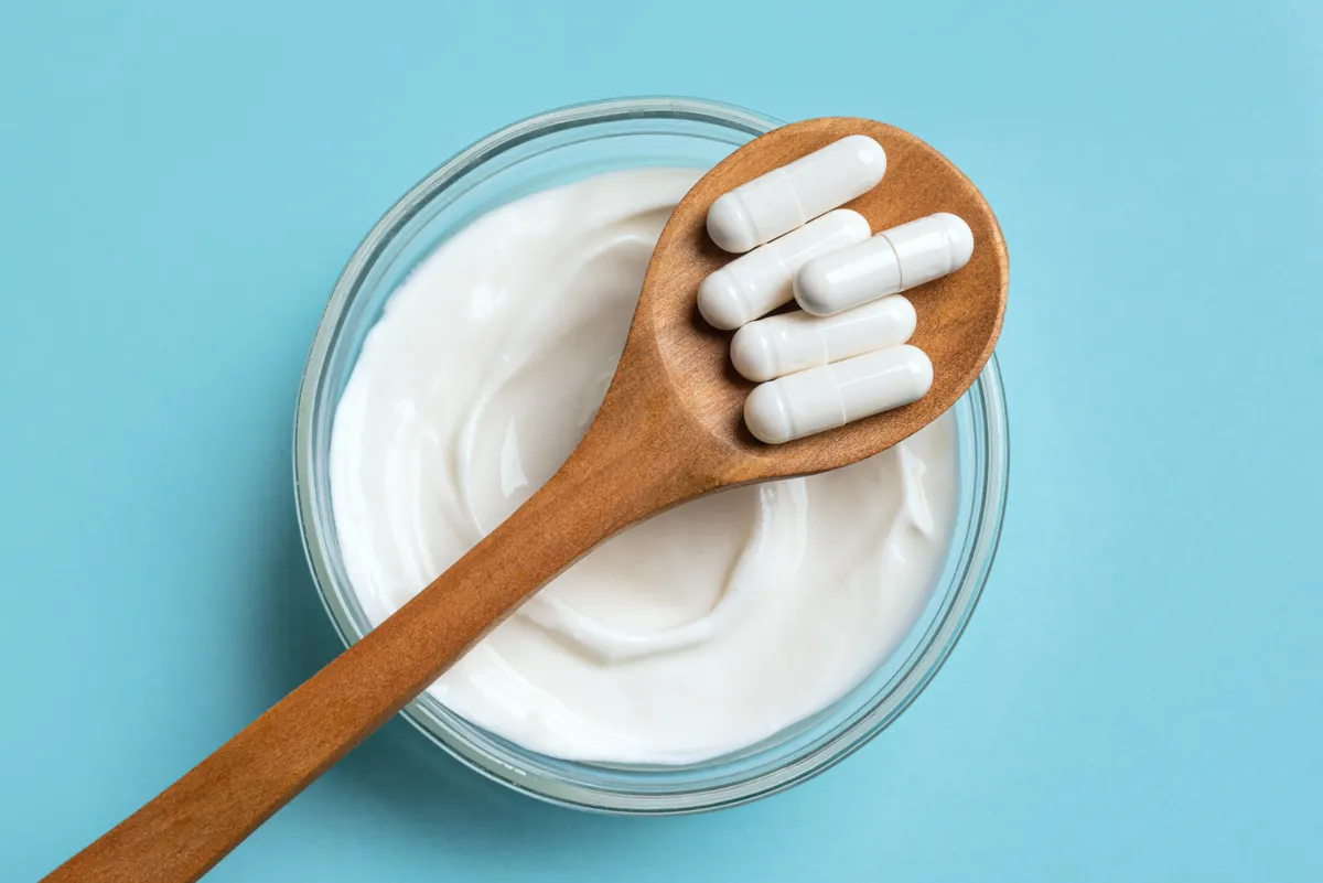 Gut health & probiotic marketing agency: probiotic capsules and bowl of yogurt on blue.