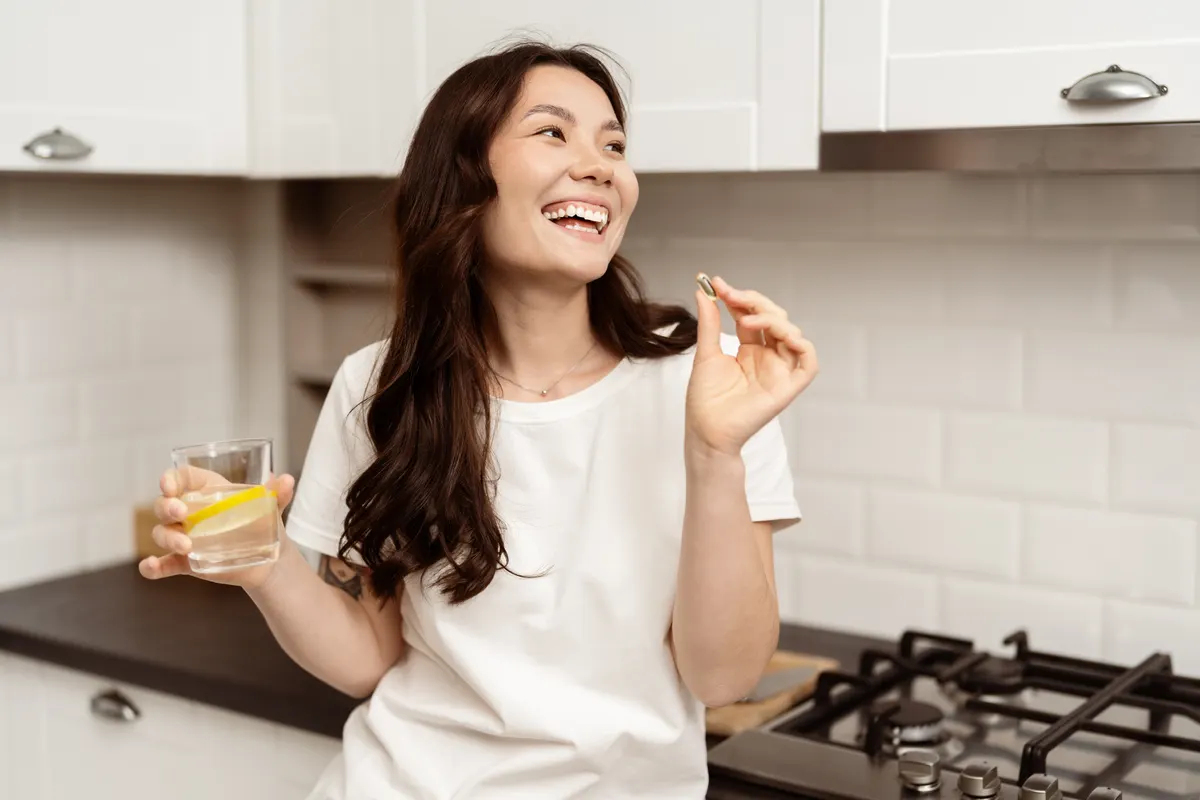 Women's vitamin marketing agency: happy Young Woman Enjoying Morning With Omega 3 In Casual Kitchen.