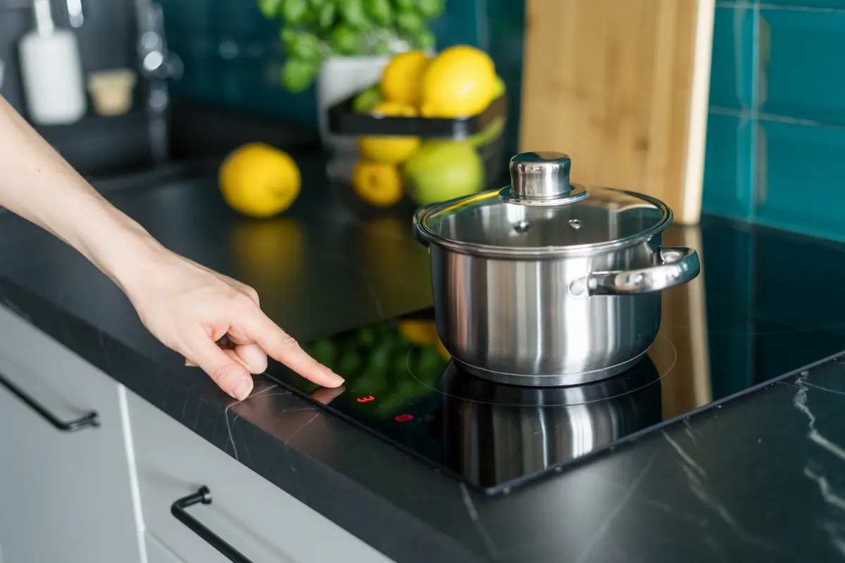 Cookware & kitchenware marketing agency: woman turn on electrical stove in modern kitchen.