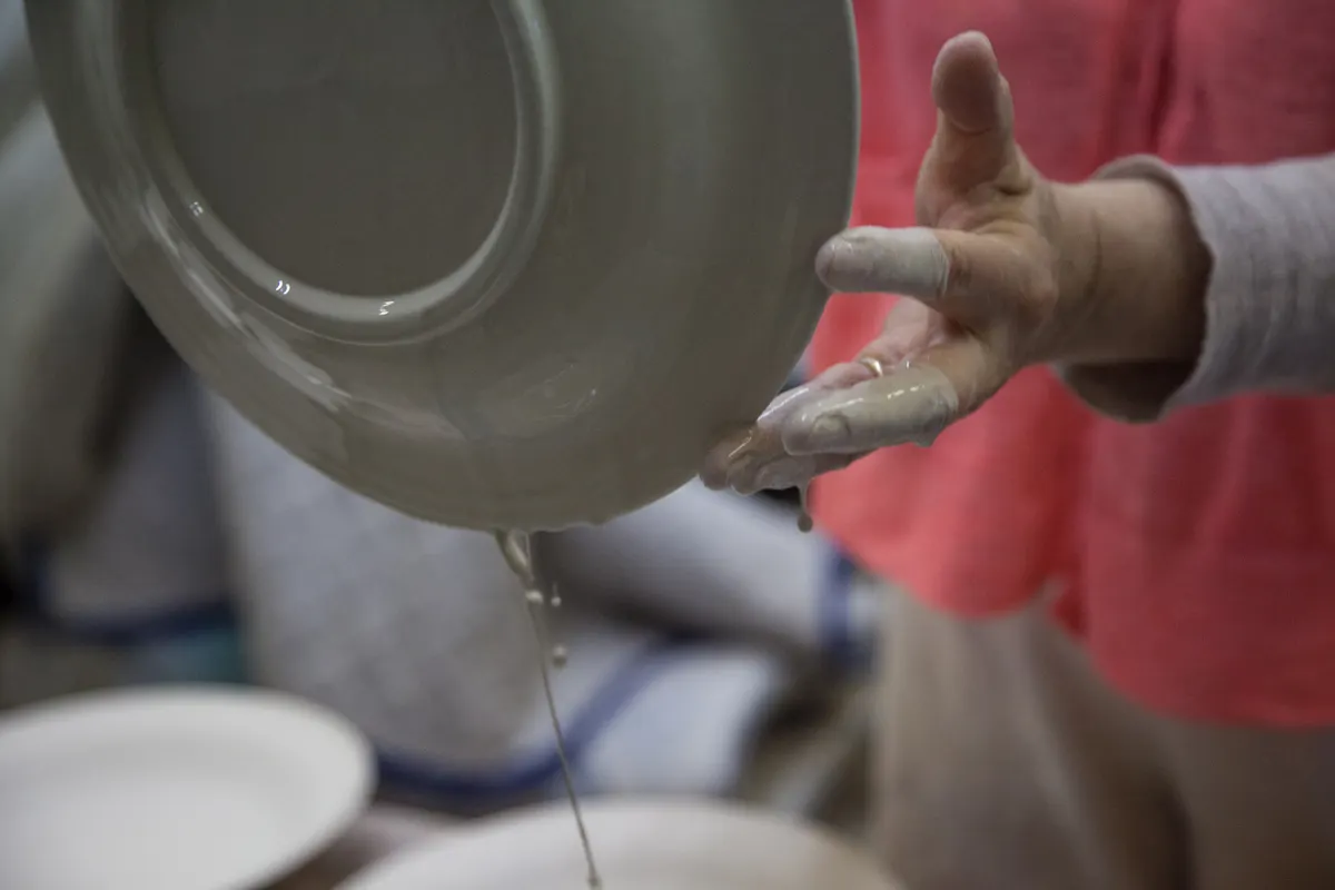 Tableware & ceramics marketing agency: angle 2, plate dripping from being dipped in ceramic glaze before firing in kiln.