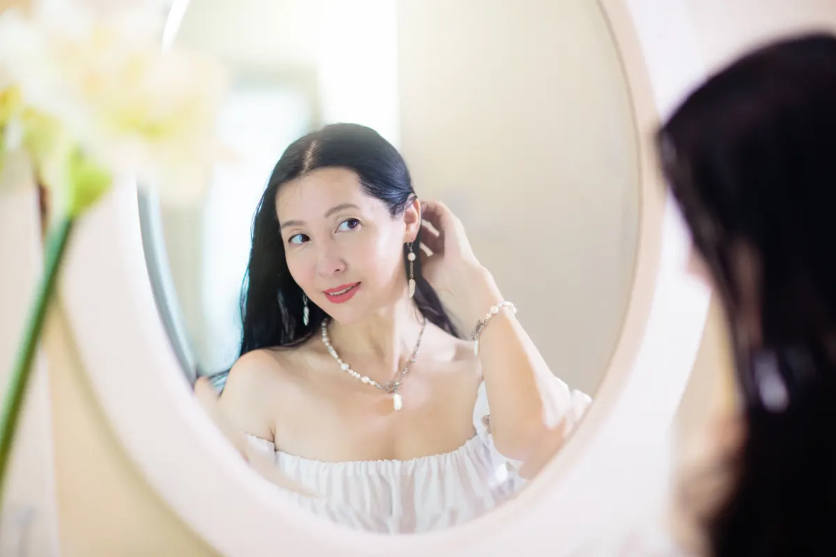 Bridal jewelry marketing agency: young Asian woman looking in the mirror.