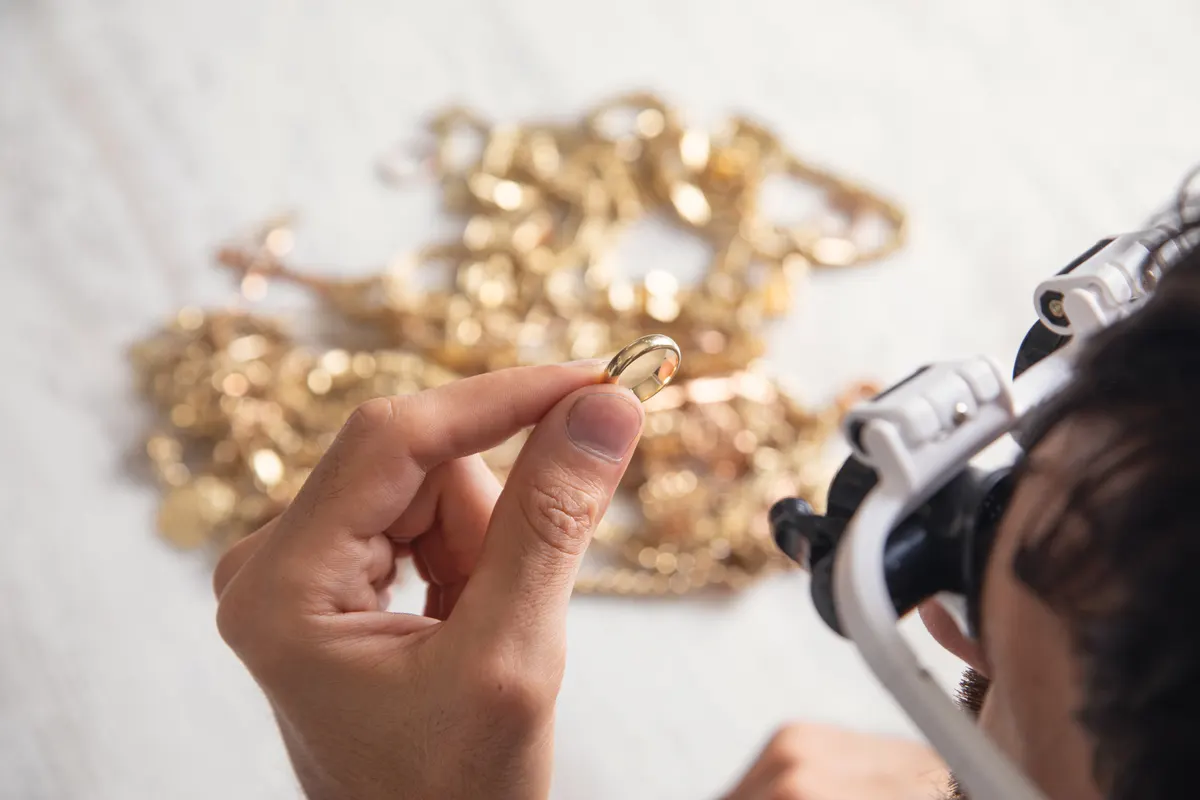 Luxury jewelry resale marketing agency: man looking at golden jewelry through a microscope.