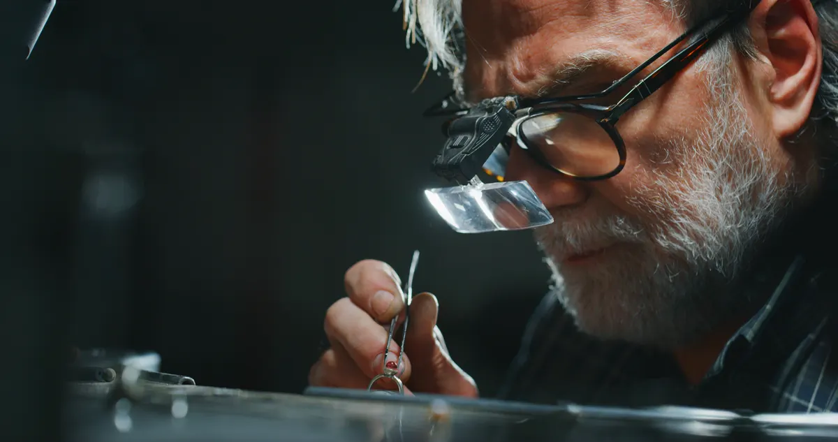 Estate jewelry marketing agency: portrait of experienced goldsmith working on a handmade jewelry ring with precious diamond stones in a workshop.
