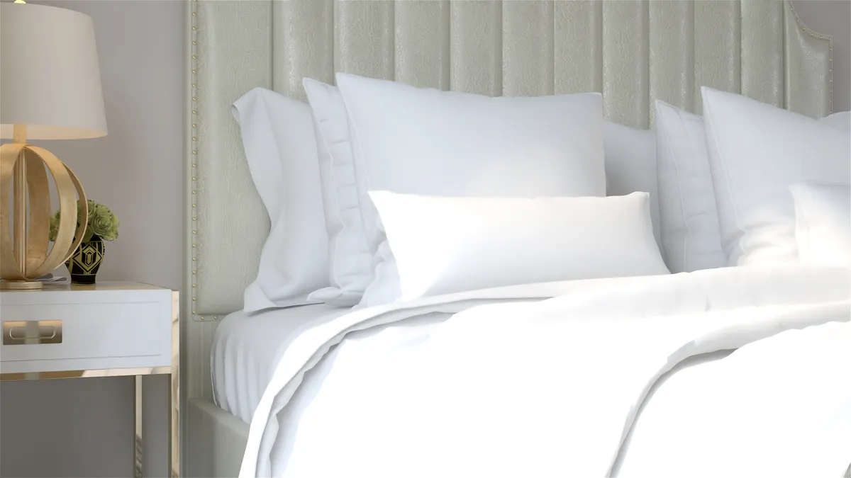 Luxury bedding marketing agency: white duvet, pillow cushion and blanket on modern and luxury design bed and bedside table with lamp in white wall bedroom with sunlight from window.
