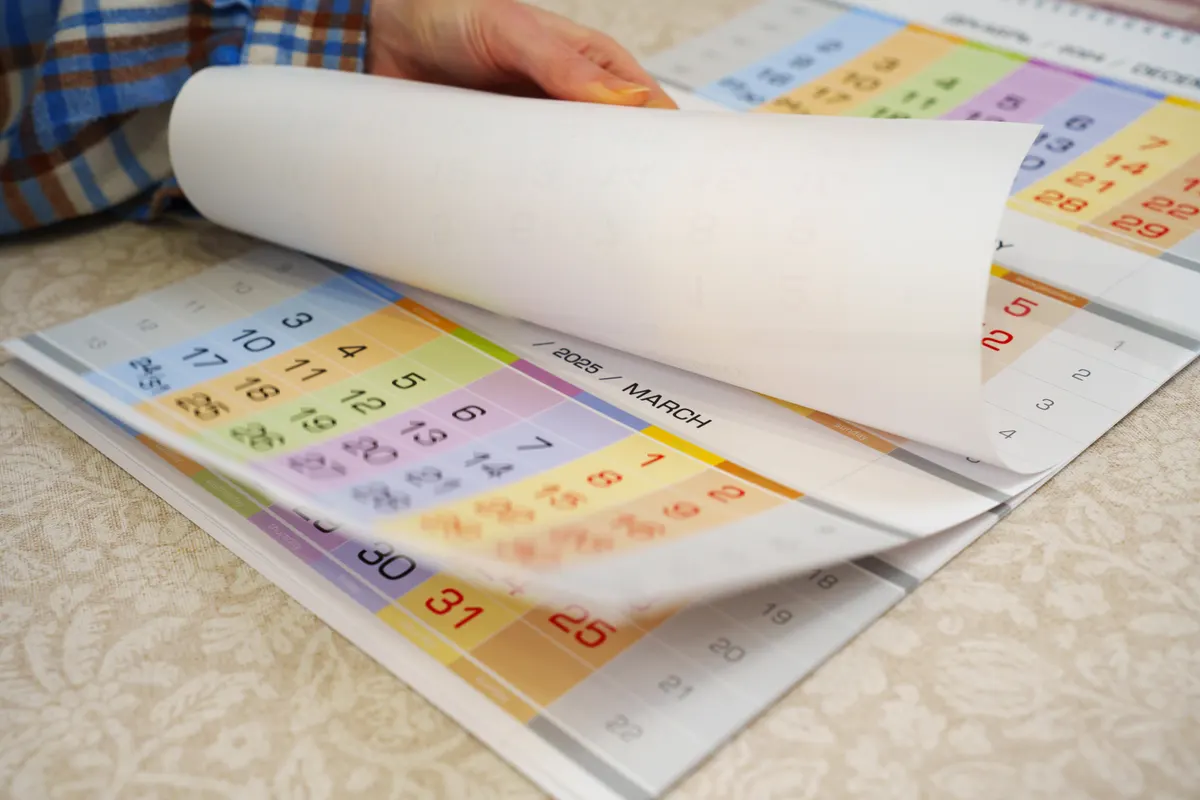 Calendar & wall art marketing agency: hand is turning the pages of a tear-off wall calendar.