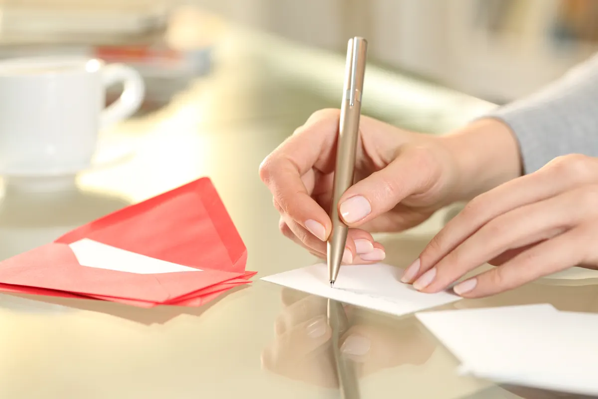 Greeting card marketing agency: woman hand writing greeting card at home.