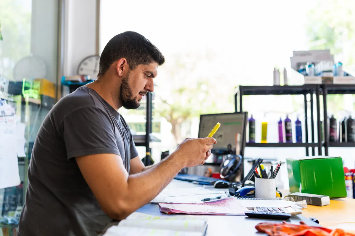 Phone case marketing agency: small business owner working in shop using mobile phone.