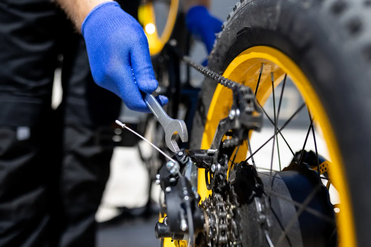 Cycling gear marketing agency: bicycle repair in progress with focus on rear gears and chain adjustment.
